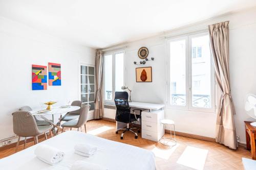 Cette chambre blanche dispose d'une table, de chaises et d'un bureau. dans l'établissement GuestReady - Elegant comfort near Panthéon, à Paris