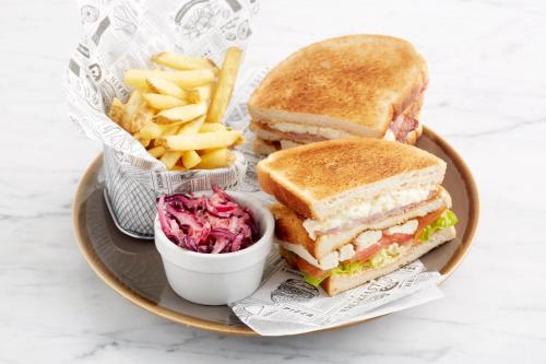 a plate with a sandwich and fries and a bowl of coleslaw at Holiday Inn Runcorn M56 Junction 12 by IHG in Runcorn
