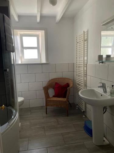 a bathroom with a sink and a chair with a red pillow at Barcloy Milk House in Kirkcudbright