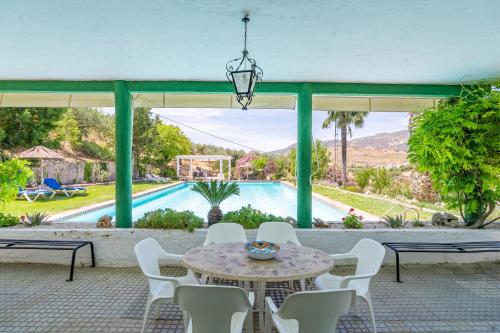 a patio with a table and chairs and a pool at Casa Rural Molino Macegal new in Carcabuey