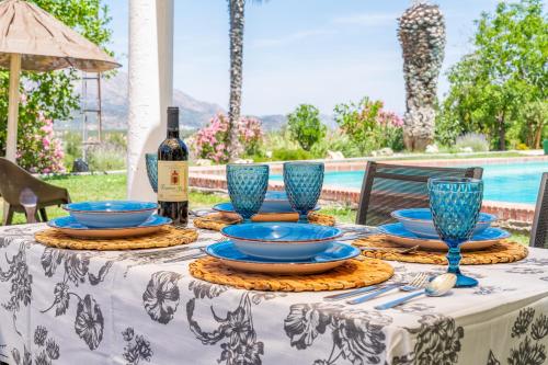 a table with blue dishes and a bottle of wine at Casa Rural Molino Macegal new in Carcabuey