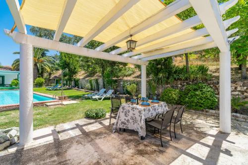 a patio with a table and chairs under a pergola at Casa Rural Molino Macegal new in Carcabuey