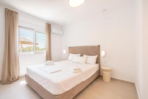 a white bedroom with a large bed and a window at CrossRhodes Villas in Pefki Rhodes