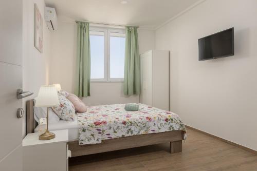 a white bedroom with a bed and a window at Olive Breeze in Brela