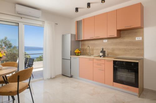 a kitchen with orange cabinets and a table with a view at Olive Breeze in Brela