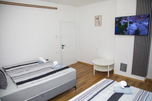 a white room with a bed and a table at Apartman Puente Viejo Mostar in Mostar