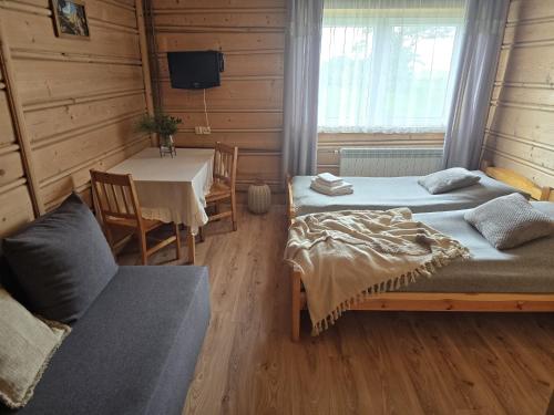 a room with two beds and a table and a table and chairs at Grota zbójnicka apartament i pokoje in Gliczarów