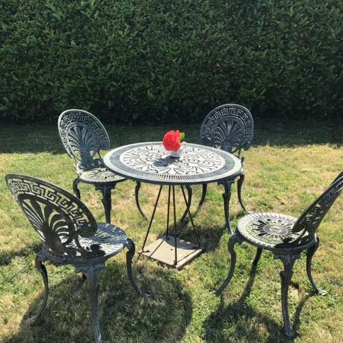 une table avec trois chaises et une table avec une fleur sur elle dans l'établissement Appartement privatif étage maison - 2 chambres - 5 couchages - Jardin, à Chavagnes-en-Paillers