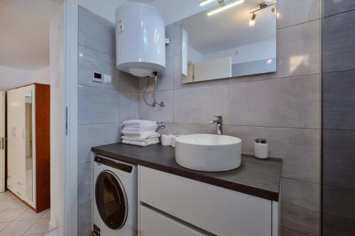 a bathroom with a sink and a washing machine at Mario in Martinšćica