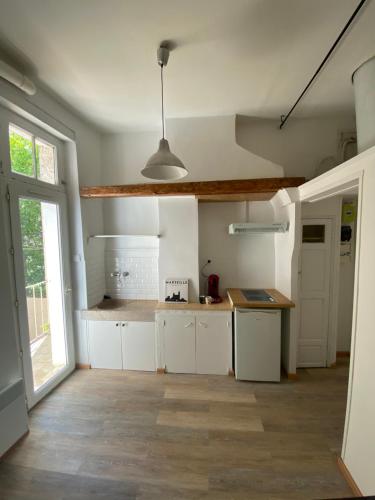 une cuisine avec des placards blancs et une grande fenêtre dans l'établissement Charmant studio au cœur du panier, à Marseille