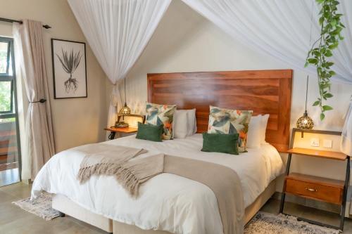 a bedroom with a large white bed with green pillows at Kasambabezi Lodge in Victoria Falls
