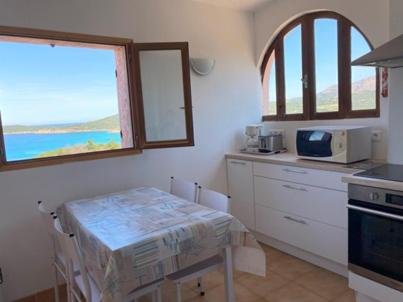 une cuisine avec une table et un four micro-ondes ainsi qu'une fenêtre dans l'établissement Appartement splendide vue mer, à Cargèse