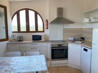 une cuisine avec des appareils électroménagers blancs et une fenêtre. dans l'établissement Appartement splendide vue mer, à Cargèse