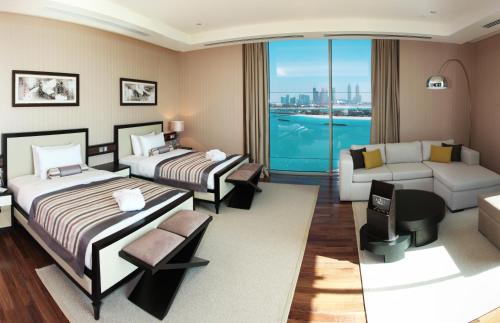 a bedroom with two beds and a living room with a couch at Rixos The Palm Hotel & Suites - Ultra All Inclusive in Dubai