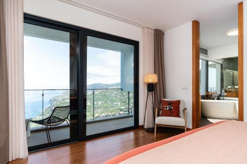 a bedroom with a bed and a balcony with a view at Valley View-Villa with heated pool and sauna in Arco da Calheta