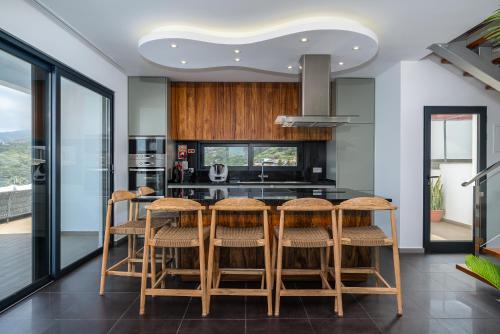a kitchen with a table with stools and a counter at Valley View-Villa with heated pool and sauna in Arco da Calheta