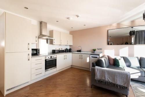 a kitchen with white cabinets and a couch in a living room at Boat House - Luxe Apt with River View - Next to Harbour & Cafes in Bristol
