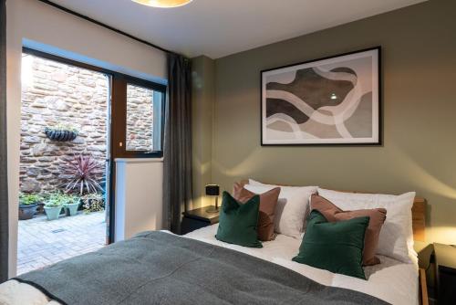 a bedroom with a large bed with green pillows at Boat House - Luxe Apt with River View - Next to Harbour & Cafes in Bristol