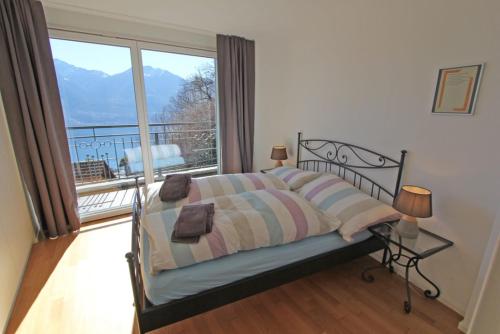 Un dormitorio con una cama y una ventana grande. en Casa Serena, 3-Zimmerwohnung-Duplex by HolAp SA, en Brione sopra Minusio