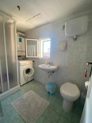 a bathroom with a toilet sink and a washing machine at Casa Senzuno - Vista mare in Follonica