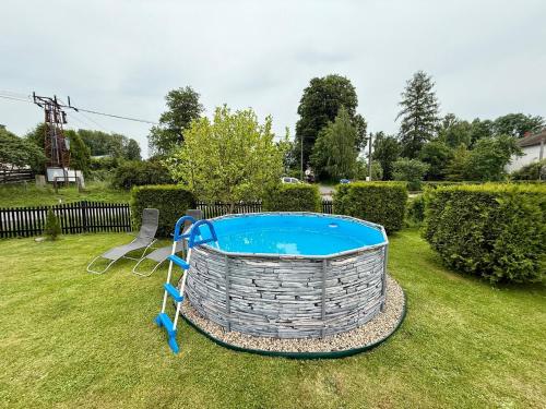 a swimming pool in a yard with two chairs at Domeček Drahuška in Janov