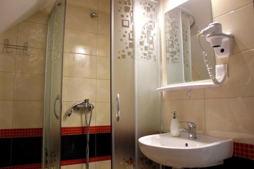a bathroom with a sink and a shower with a mirror at Pokoje Gościnne u Kovi in Legnica