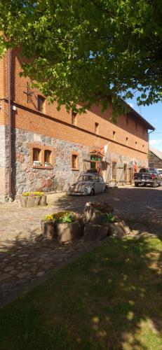 a car parked in front of a brick building at Hotel Spichrz in Borcz