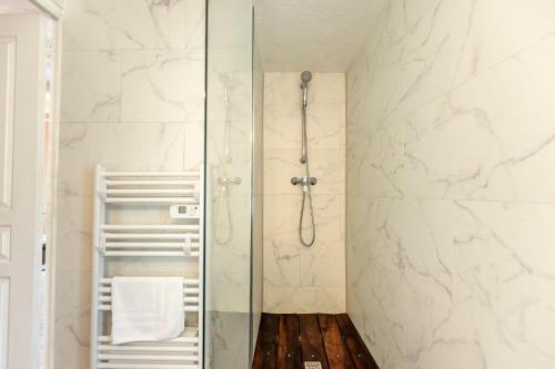 La salle de bains est pourvue d'une douche et de murs en marbre blanc. dans l'établissement La Pierre Blanche - Maison Familiale, à Saint-Georges-sur-Cher