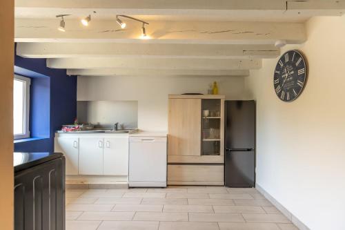 une cuisine avec des appareils blancs et une horloge murale dans l'établissement La Pierre Blanche - Maison Familiale, à Saint-Georges-sur-Cher