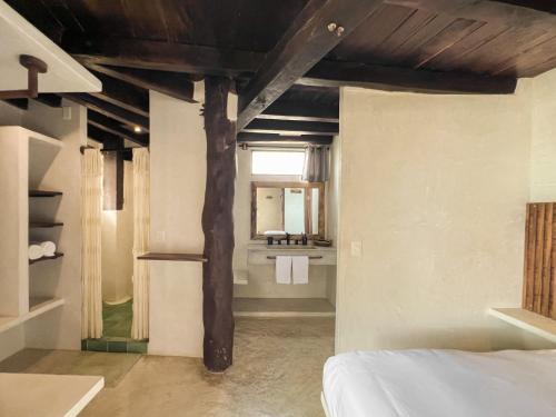 a bedroom with a bed and a bathroom with a sink at Chica in Tulum