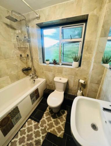 a bathroom with a toilet and a tub and a sink at Surrey Hills Retreat - 2-Bed - Easy London Access in Ash