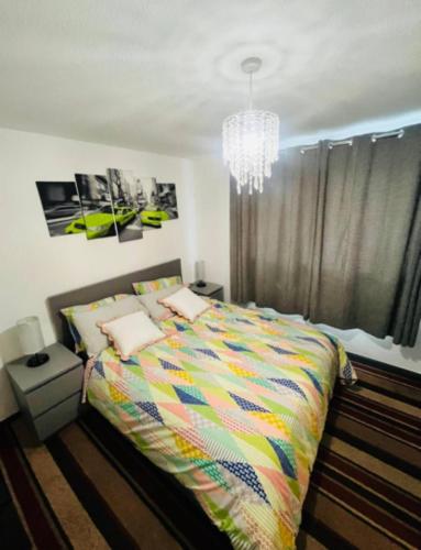 a bedroom with a colorful bed and a chandelier at Surrey Hills Retreat - 2-Bed - Easy London Access in Ash