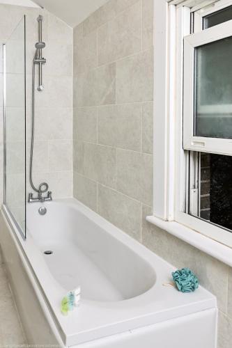 a bath tub in a bathroom with a tv at 4-Bed Cottage Sleeps 8 Walk to Thames Garden in Hampton