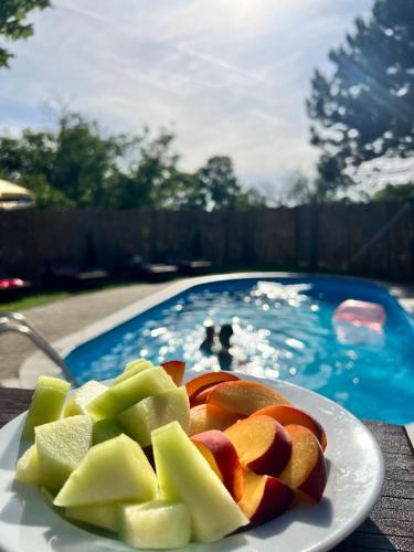 a plate of fruit on a table next to a swimming pool at Pool House in Subotica