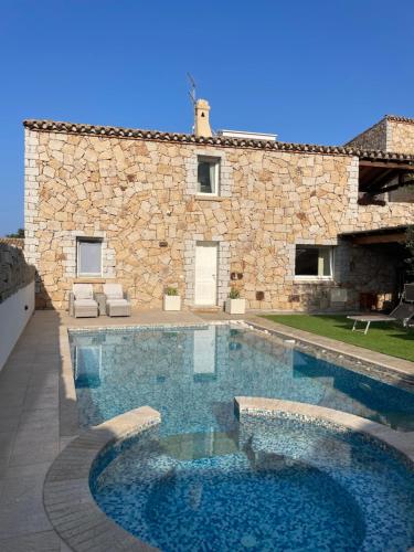 a swimming pool in front of a stone house at Villa Grazia in Cala Sinzias