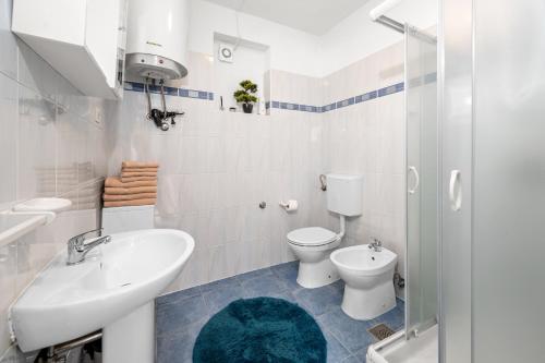 Un baño blanco con inodoro y lavabo. en Villa Fortuna, en Labin