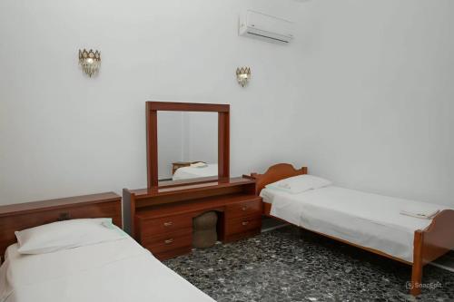 two beds in a room with a mirror and a desk at Anna's Traditional House Pandeli in Panteli