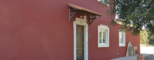 a red building with a door on the side of it at Villa Monte da Alfarrobeira in Estói