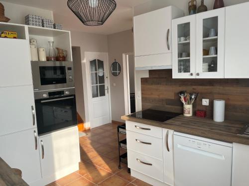 une cuisine avec des armoires blanches et un comptoir dans l'établissement Buxerioux Retreat, à Châteauroux