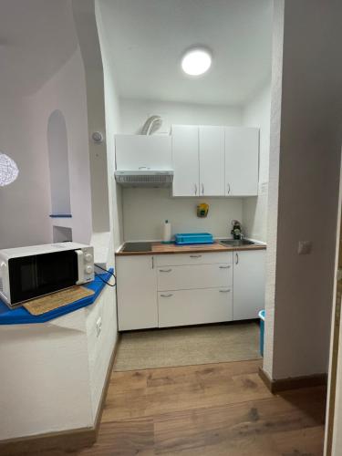 una pequeña cocina con armarios blancos y microondas en Piera's Paraiso Seaview, en Playa Paraiso
