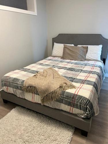 a bed with a blanket and a rug in a bedroom at Gorgeous Basement Apartment in Calgary