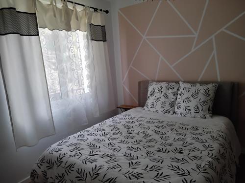 une chambre avec un lit noir et blanc et une fenêtre dans l'établissement Bienvenue chez Rosy, au Mans