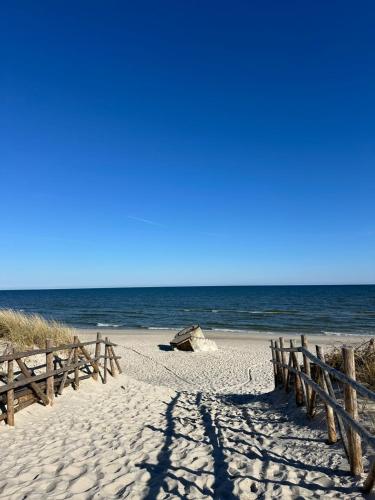 a sandy beach with a wooden fence and the ocean at Makihyte dom na wyłączność z panoramą na morze i strefą SPA in Sasino