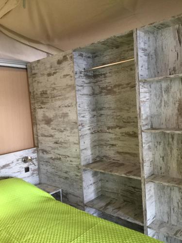 a bedroom with a green bed and wooden walls at Parco Del Lago Glamping And Camping in Anguillara Sabazia