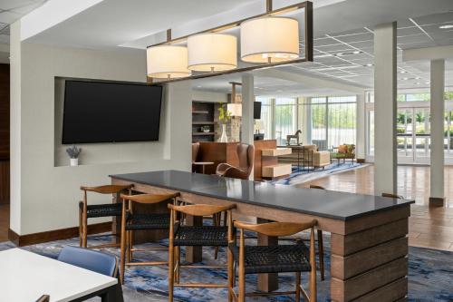 ミッドベールにあるFairfield Inn & Suites by Marriott Salt Lake City Midvaleの椅子と薄型テレビのあるバーを備えたオフィスロビー