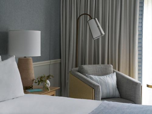 a bedroom with a bed and a chair and a lamp at Wequassett Resort and Golf Club in East Harwich