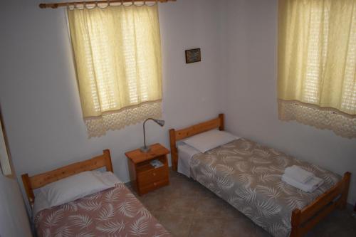 a room with two beds and a lamp and two windows at Under the pine tree in Divarata