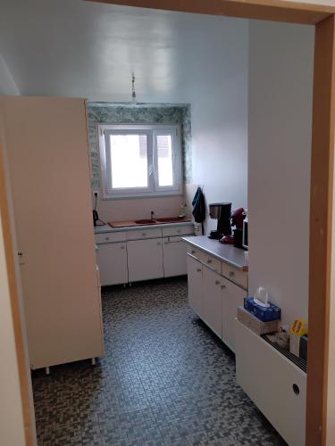 une cuisine avec des armoires blanches et une fenêtre dans l'établissement Bienvenue chez Rosy, au Mans