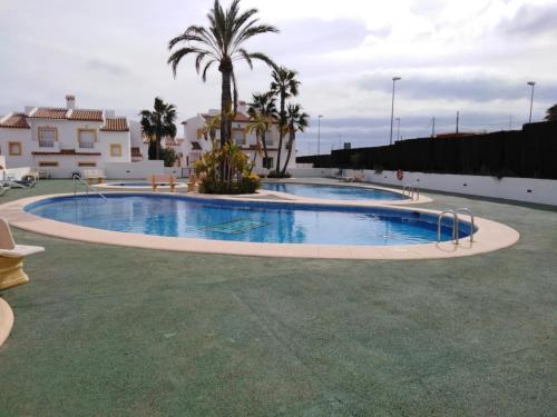 Una gran piscina con palmera y edificios. en Bungalow Puerta de Calpe, en Calpe