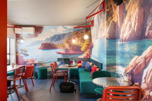 a restaurant with a large painting on the wall at Greet Hotel Nice Aéroport Promenade des Anglais in Nice
